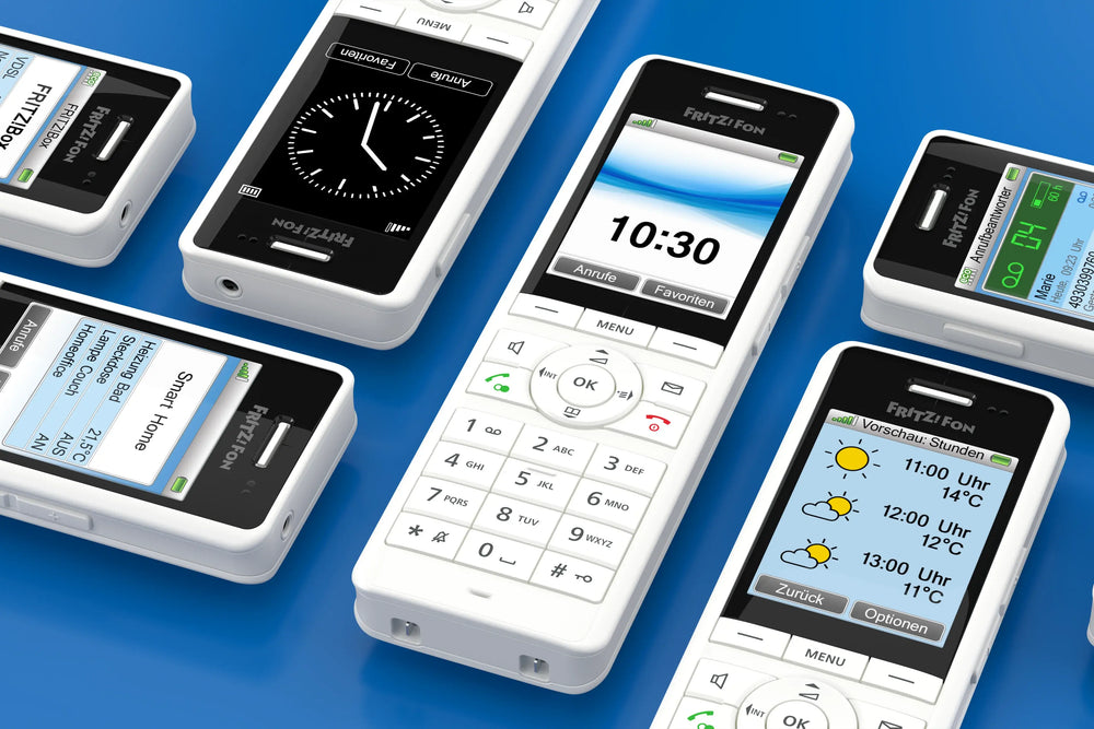 Verschiedene FRITZ!Fon Telefone auf blauer Oberfläche mit Uhr und Wetteranzeige.